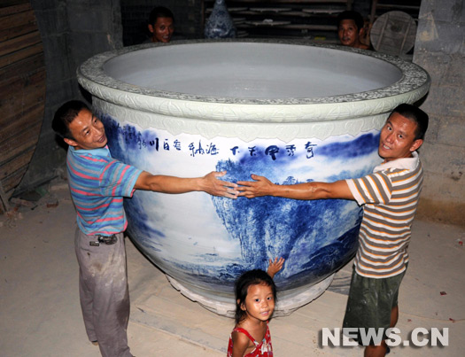 Il faut quatre adultes pour faire le tour du colossal vase 'bleu et blanc' en porcelaine de 1,36 m de hauteur, d'un diamètre intérieur de 2 m, de 6,8 m de circonférence extérieure à son ouverture et un poids total de plus de 1 500 kg, produit à Jingdezhen, dans la province du Jiangxi (est).