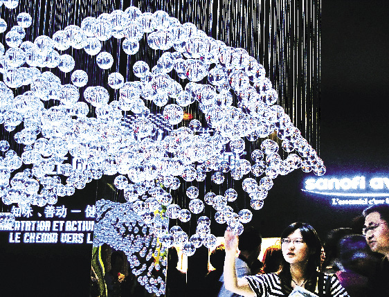 Dans la zone de Sanofi-Aventis du pavillon de la France, des visiteurs passent au-dessous de l&rsquo;installation d&rsquo;un syst&egrave;me mol&eacute;culaire.